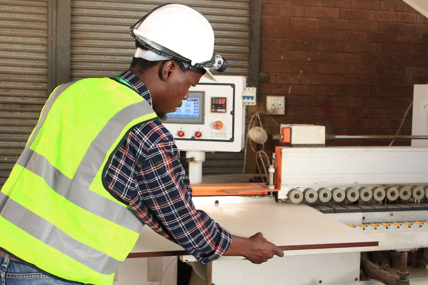 Tshitanda team member feeding a board into the edge banding machine